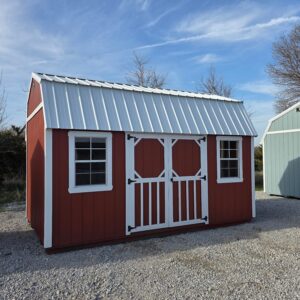 Exterior of a wide shed with double doors and two windows in the front.