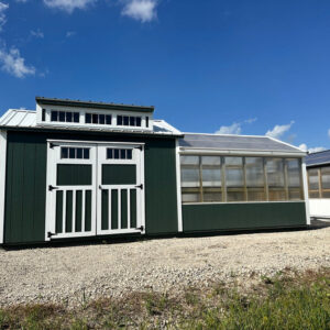 Exterior of green and white greenhouse with shed attached.