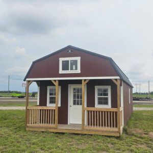 Exterior of a large, metal-sided cabin featuring a wood front porch, and a loft with a window