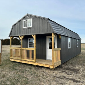 Exterior of a long cabin or ADU with a wood porch and loft window.