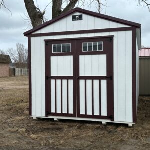 Exterior of white and brown shed on cinderblocks.