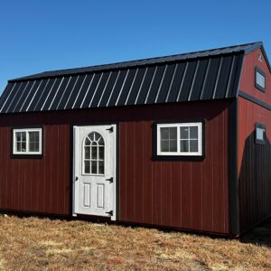 Exterior of large shed, showcasing a door and two windows with white trim.