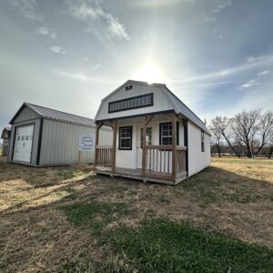 Exterior of a small white cabin, showcasing the front porch and horizontal window in lofted area.